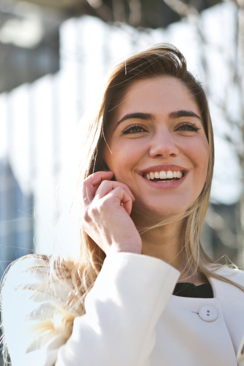 Confident businesswoman using her tablet and phone, smiling outdoors in sunlight.